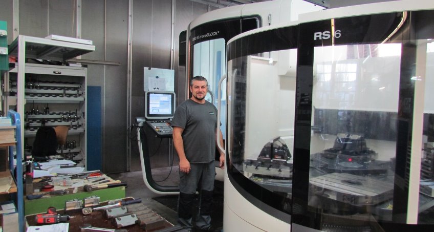 Ein Facharbeiter steht vor modernen CNC-Fräsmaschinen in einer industriellen Werkstatt.